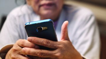 Low Angle View Of Woman Using Phone While Lying On Bed