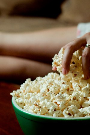 Woman hand into bowl of popcorn. National Popcorn Day