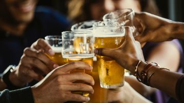 Group of friends toasting beer glasses at table in bar - stock photo