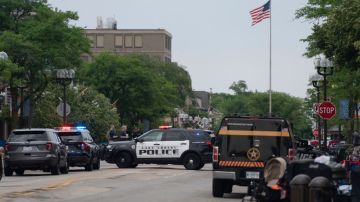 Officers guard the scene of the Fourth of July parade shooting in Highland Park, Illinois on July 4, 2022. - A shooter opened fire Monday during a parade to mark US Independence Day in the state of Illinois, killing at least six people, officials said. "At this time, two dozen people have been transported to Highland Park hospital. Six are confirmed deceased," Commander Chris O'Neil of the city's police told journalists. The suspected shooter, who is still at large, has been described as a white male aged 18-20 with longer black hair, O'Neil said. (Photo by Youngrae Kim / AFP) (Photo by YOUNGRAE KIM/AFP via Getty Images)