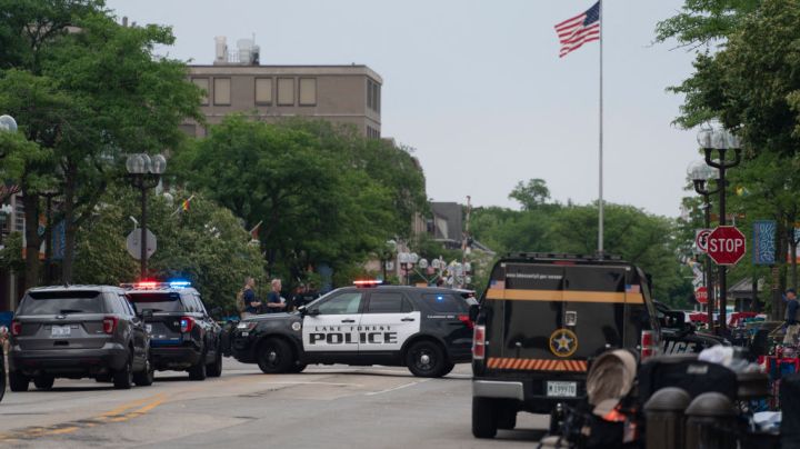 Officers guard the scene of the Fourth of July parade shooting in Highland Park, Illinois on July 4, 2022. - A shooter opened fire Monday during a parade to mark US Independence Day in the state of Illinois, killing at least six people, officials said. "At this time, two dozen people have been transported to Highland Park hospital. Six are confirmed deceased," Commander Chris O'Neil of the city's police told journalists. The suspected shooter, who is still at large, has been described as a white male aged 18-20 with longer black hair, O'Neil said. (Photo by Youngrae Kim / AFP) (Photo by YOUNGRAE KIM/AFP via Getty Images)