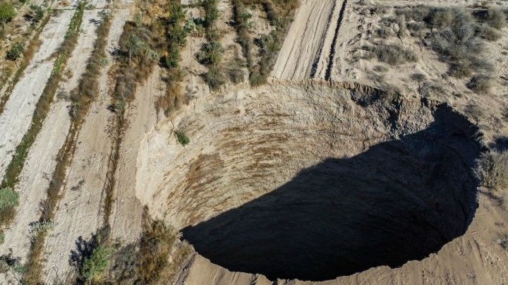 TOPSHOT - Aerial view taken on August 1, 2022, showing a large sinkhole that appeared over the weekend near the mining town of Tierra Amarilla, Copiapo Province, in the Atacama Desert in Chile. - A 100-metre security perimeter has been erected around the hole which appeared in the Tierra Amarilla municipality near the Alcaparrosa mine operated by Canadian firm Lundin Mining. (Photo by JOHAN GODOY / AFP) (Photo by JOHAN GODOY/AFP via Getty Images)