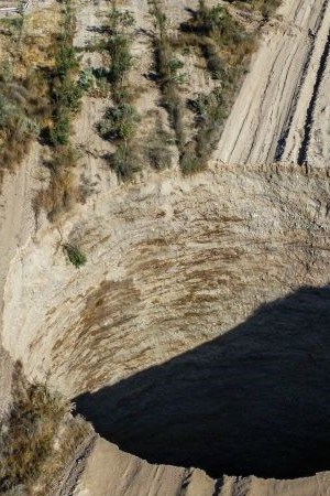 TOPSHOT - Aerial view taken on August 1, 2022, showing a large sinkhole that appeared over the weekend near the mining town of Tierra Amarilla, Copiapo Province, in the Atacama Desert in Chile. - A 100-metre security perimeter has been erected around the hole which appeared in the Tierra Amarilla municipality near the Alcaparrosa mine operated by Canadian firm Lundin Mining. (Photo by JOHAN GODOY / AFP) (Photo by JOHAN GODOY/AFP via Getty Images)