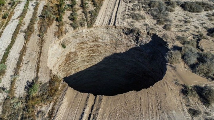 TOPSHOT - Aerial view taken on August 1, 2022, showing a large sinkhole that appeared over the weekend near the mining town of Tierra Amarilla, Copiapo Province, in the Atacama Desert in Chile. - A 100-metre security perimeter has been erected around the hole which appeared in the Tierra Amarilla municipality near the Alcaparrosa mine operated by Canadian firm Lundin Mining. (Photo by JOHAN GODOY / AFP) (Photo by JOHAN GODOY/AFP via Getty Images)
