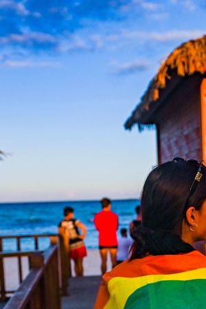 Dancers walk to the beach with a rainbow flag at the Gran Muthu Rainbow Hotel located Guillermo Key in Ciego de Avila Province, Cuba on November 27, 2021. - Cuba's first LGBT hotel, which had been inaugurated in December 2019, but very soon had to close due to the coronavirus pandemic, reopened to attract that tourist segment at a time when authorities are studying the approval of equal marriage on the island. Under all preventive sanitary measures, this five-star accommodation received its first clients again on November 15, when Cuba reopened its borders after 10 months of confinement. (Photo by YAMIL LAGE / AFP) (Photo by YAMIL LAGE/AFP via Getty Images)