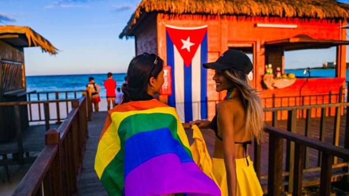Dancers walk to the beach with a rainbow flag at the Gran Muthu Rainbow Hotel located Guillermo Key in Ciego de Avila Province, Cuba on November 27, 2021. - Cuba's first LGBT hotel, which had been inaugurated in December 2019, but very soon had to close due to the coronavirus pandemic, reopened to attract that tourist segment at a time when authorities are studying the approval of equal marriage on the island. Under all preventive sanitary measures, this five-star accommodation received its first clients again on November 15, when Cuba reopened its borders after 10 months of confinement. (Photo by YAMIL LAGE / AFP) (Photo by YAMIL LAGE/AFP via Getty Images)