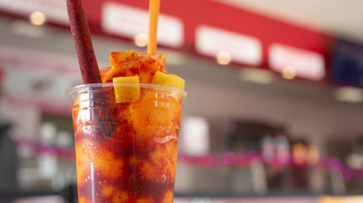 A view of a mangonada drink, in a restaurant interior setting.