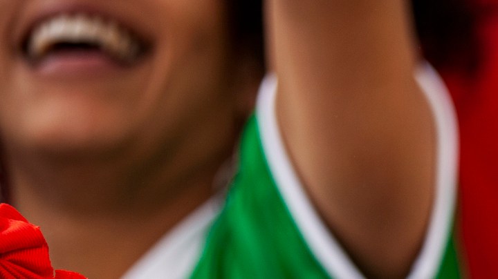 Front view portrait of Mexican football wearing Lucha Libre wrestling mask while watching international championship match at stadium