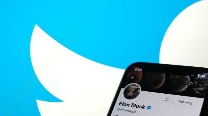 This illustration photo taken May 13, 2022, displays Elon Musks Twitter account with a Twitter logo in the background in Los Angeles. - Elon Musk sent mixed messages Friday about his proposed Twitter acquisition, pressuring shares of the microblogging platform amid skepticism on whether the deal will close. In an early morning tweet, Musk said the $44 billion takeover was "temporarily on hold," pending questions over the social media company's estimates of the number of fake accounts or "bots." That sent Twitter's stock plunging 25 percent. (Photo by Chris DELMAS / AFP) (Photo by CHRIS DELMAS/AFP via Getty Images)