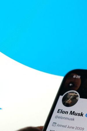 This illustration photo taken May 13, 2022, displays Elon Musks Twitter account with a Twitter logo in the background in Los Angeles. - Elon Musk sent mixed messages Friday about his proposed Twitter acquisition, pressuring shares of the microblogging platform amid skepticism on whether the deal will close. In an early morning tweet, Musk said the $44 billion takeover was "temporarily on hold," pending questions over the social media company's estimates of the number of fake accounts or "bots." That sent Twitter's stock plunging 25 percent. (Photo by Chris DELMAS / AFP) (Photo by CHRIS DELMAS/AFP via Getty Images)