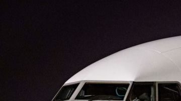 Members of the Argentinian team peer out from the windows on their plane adorned with a picture of Argentina's forward Lionel Messi and teammates as the team arrives at the Hamad International Airport in Doha on November 17, 2022, ahead of the Qatar 2022 World Cup football tournament. (Photo by Odd ANDERSEN / AFP) (Photo by ODD ANDERSEN/AFP via Getty Images)