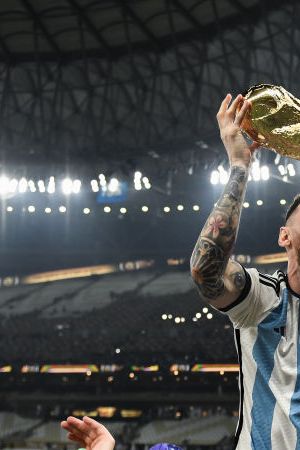 LUSAIL CITY, QATAR - DECEMBER 18: Lionel Messi of Argentina celebrates with the FIFA World Cup Qatar 2022 Winner's Trophy on Sergio 'Kun' Aguero's shoulders after the team's victory during the FIFA World Cup Qatar 2022 Final match between Argentina and France at Lusail Stadium on December 18, 2022 in Lusail City, Qatar. (Photo by David Ramos - FIFA/FIFA via Getty Images)