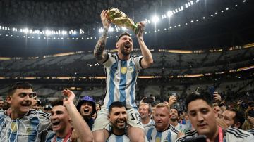 LUSAIL CITY, QATAR - DECEMBER 18: Lionel Messi of Argentina celebrates with the FIFA World Cup Qatar 2022 Winner's Trophy on Sergio 'Kun' Aguero's shoulders after the team's victory during the FIFA World Cup Qatar 2022 Final match between Argentina and France at Lusail Stadium on December 18, 2022 in Lusail City, Qatar. (Photo by David Ramos - FIFA/FIFA via Getty Images)