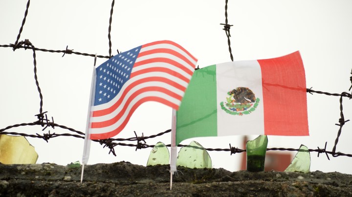 U.S. and Mexico border wall with flags