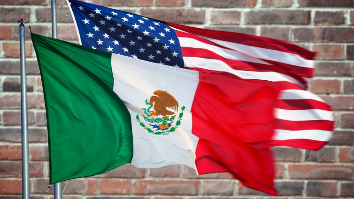 Mexican and American flag with wall behind