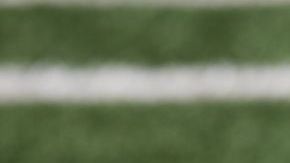 American football ball at yard line markers on playing field - stock photo