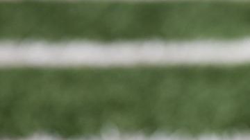 American football ball at yard line markers on playing field - stock photo