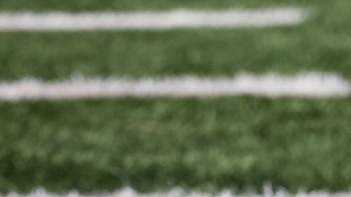 American football ball at yard line markers on playing field - stock photo
