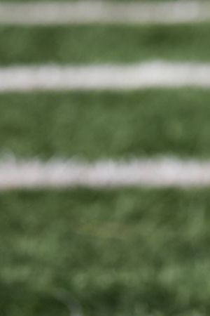 American football ball at yard line markers on playing field - stock photo