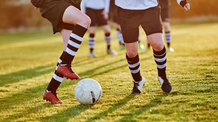 Close up of female footballer's footwork to avoid being tackled, in warm evening light