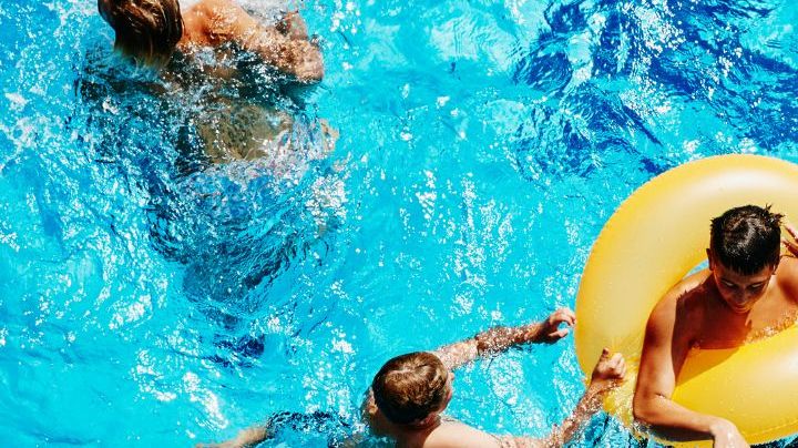 Group of kids playing together in outdoor pool overhead view