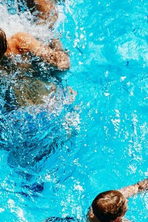 Group of kids playing together in outdoor pool overhead view