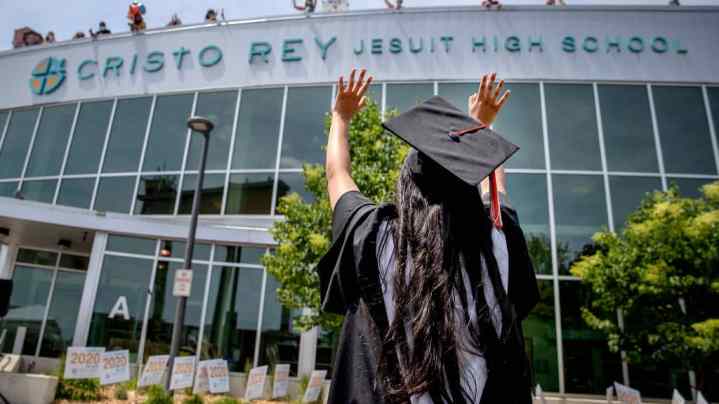 Graduation student waving at school.