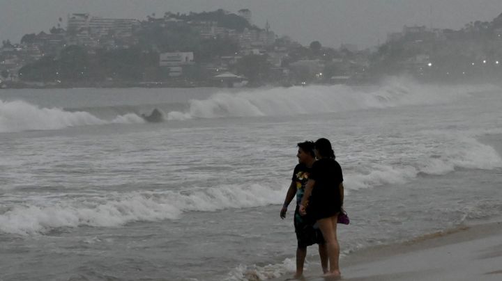 People stand on the beach after Hurricane Otis' arrival alert in Acapulco, Guerrero state, Mexico on October 24, 2023. A new Category 3 hurricane, driven by winds exceeding 200 km/h, threatens Acapulco, the tourist capital of the Pacific on the west coast of Mexico, the American National Hurricane Center (NHC) said on Tuesday. (Photo by FRANCISCO ROBLES / AFP) (Photo by FRANCISCO ROBLES/AFP via Getty Images)
