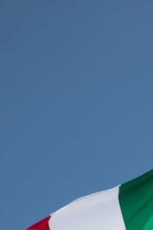 Bottom View of Passenger Airplane Flying Over Waving Mexico Flag On Pole.