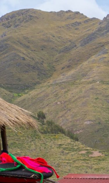 Three local female weavers in colourful traditional local dress including festooned hats, weaving colourful alpaca wool on the ground, Chumbe Community, Lamay, Sacred Valley, Peru (3 Model Releases and Property Release) - stock photo
