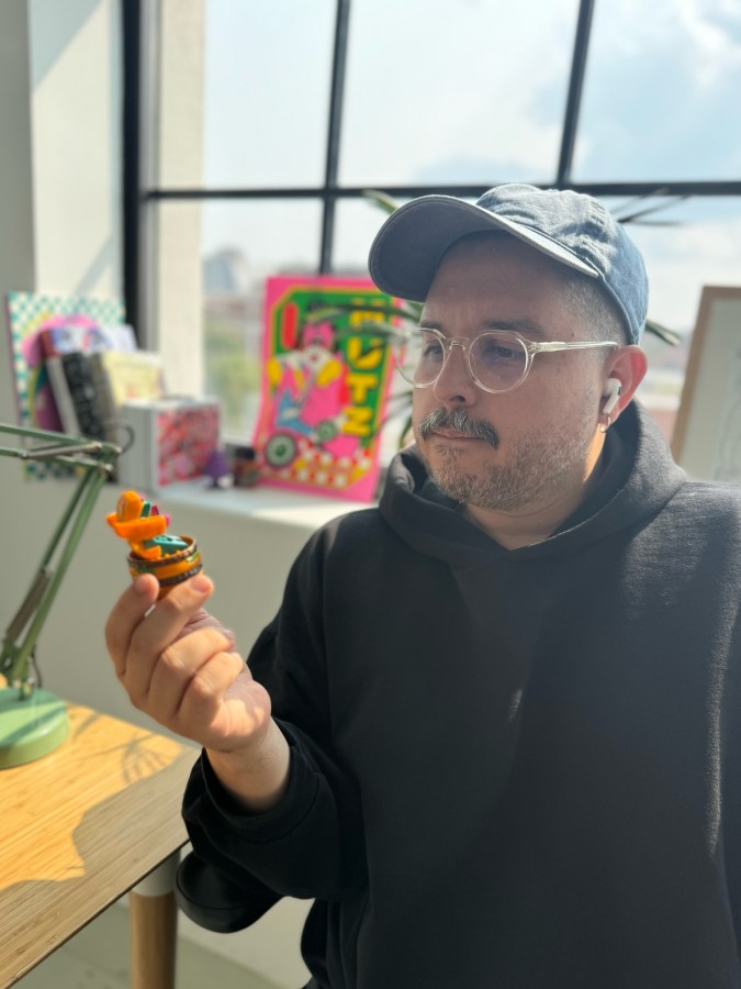 Oscar Bastidas with Macro Mac, a small, plastic toy that transformed from McDonald’s signature Big Mac hamburger into a robot.
