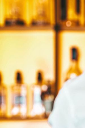 Barman making cocktail at night club bar - Bartender pouring alcohol from shaker into martini glass - Beverage life style concept