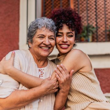Portrait of grandmother and granddaughter embracing outdoors - stock photo