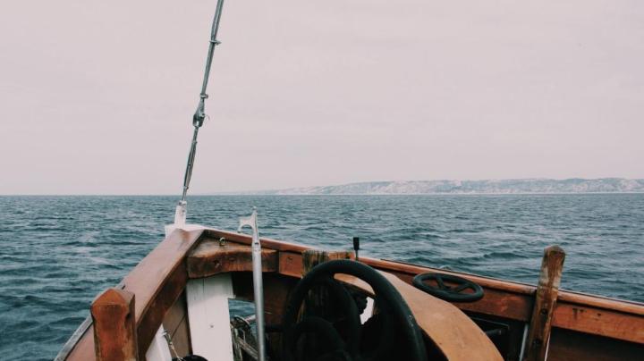 Beautiful shot of a bow of the boat on the sea with hills and a cloudy in the background