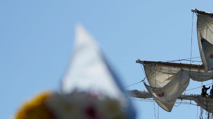 Flags, flowers and other tributes are left on a fence near the Cuauhtemoc, a masted Mexican Navy training ship, after it collided with the Brooklyn Bridge in New York, Monday, May 19, 2025. (AP Photo/Seth Wenig)