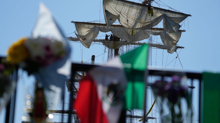 Flags, flowers and other tributes are left on a fence near the Cuauhtemoc, a masted Mexican Navy training ship, after it collided with the Brooklyn Bridge in New York, Monday, May 19, 2025. (AP Photo/Seth Wenig)