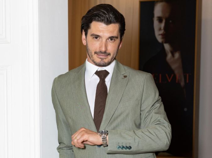 Yon González looking at the camera as he lifts up hand to look at watch