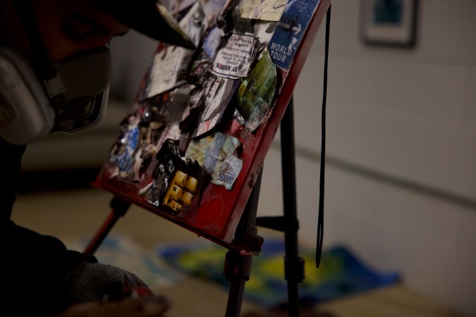 Bxlyfe working in front of an easel with a venilator on