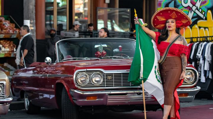 Women with a red sombrero and Mexico flag standing in front of a red lowrider