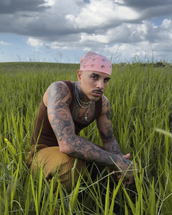 Rauw Alejandro crouching in field