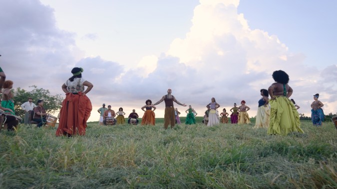Rauw Alejandro in a field with singers and dancers around him